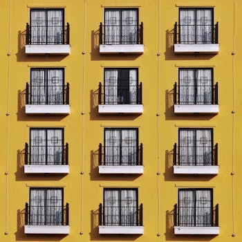 A repetitive pattern of balconies on a vibrant yellow building facade.