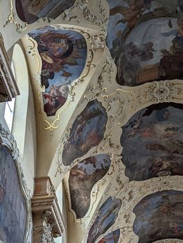 Intricate Baroque ceiling art with religious themes in a Prague church.