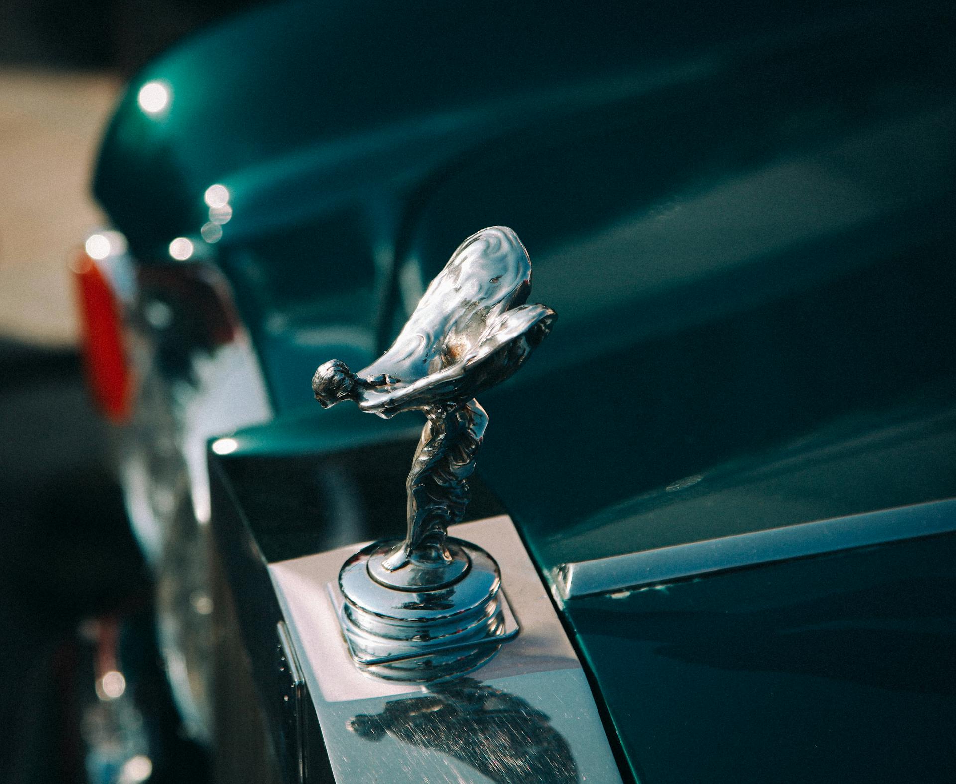 A detailed view of a luxury car emblem on a glossy green vehicle, showcasing elegance.