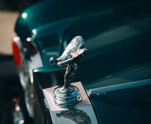 Free A detailed view of a luxury car emblem on a glossy green vehicle, showcasing elegance. Stock Photo