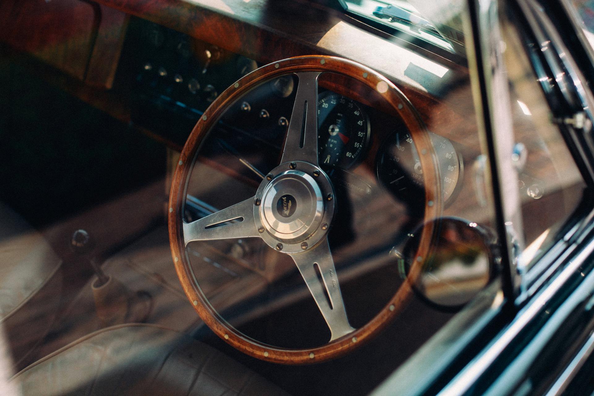 Close-up of a vintage car interior showcasing a classic wooden steering wheel and retro dashboard.