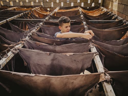 Free Young boy working in a rustic leather tannery, displaying traditional methods. Stock Photo