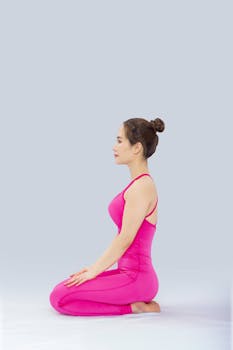 Side profile of a woman in a pink yoga outfit meditating indoors.