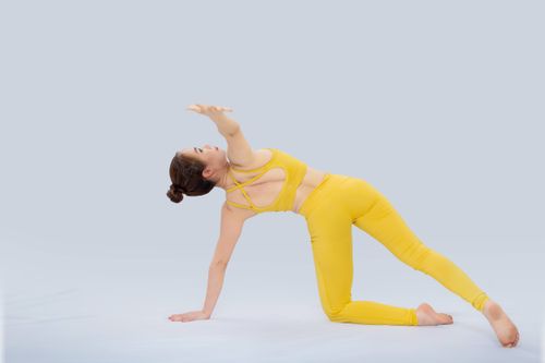 Free An Asian woman in vibrant sportswear performing yoga on a plain background. Stock Photo