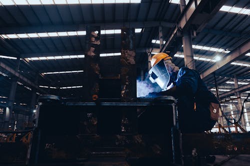Man in a Protective Mask Doing Metalwork in a Workshop 
