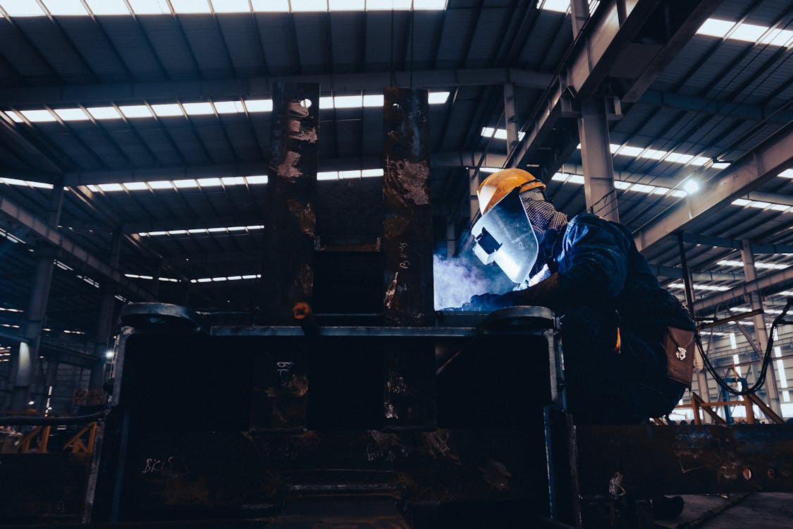 Man in a Protective Mask Doing Metalwork in a Workshop 