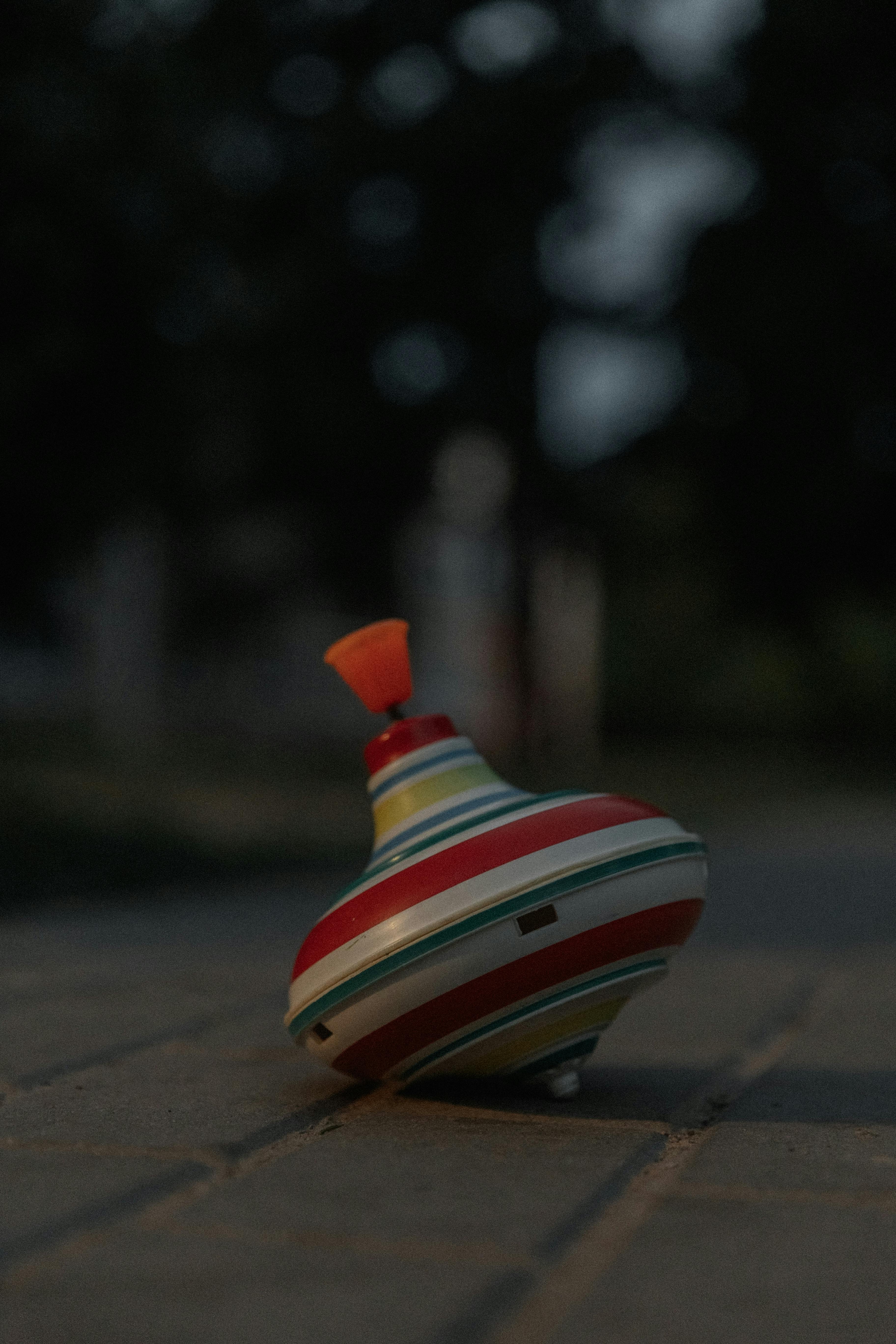 Vibrant toy spinning top with stripes captured during twilight outdoors with bokeh effect.