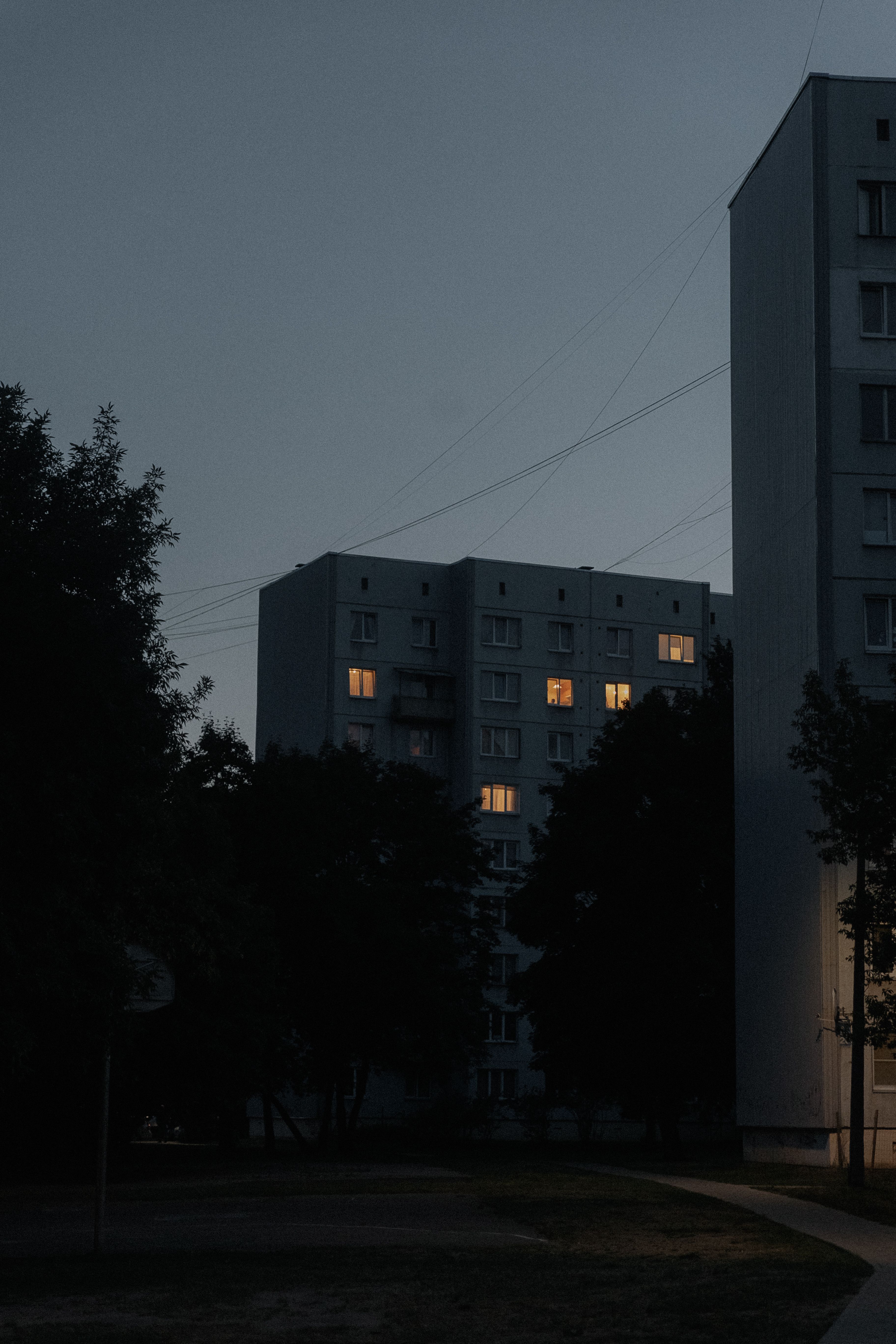Dark, atmospheric view of urban residential buildings with lights on at twilight.