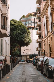 A picturesque urban scene in Valencia, Spain, featuring modern buildings and parked cars on a narrow street.