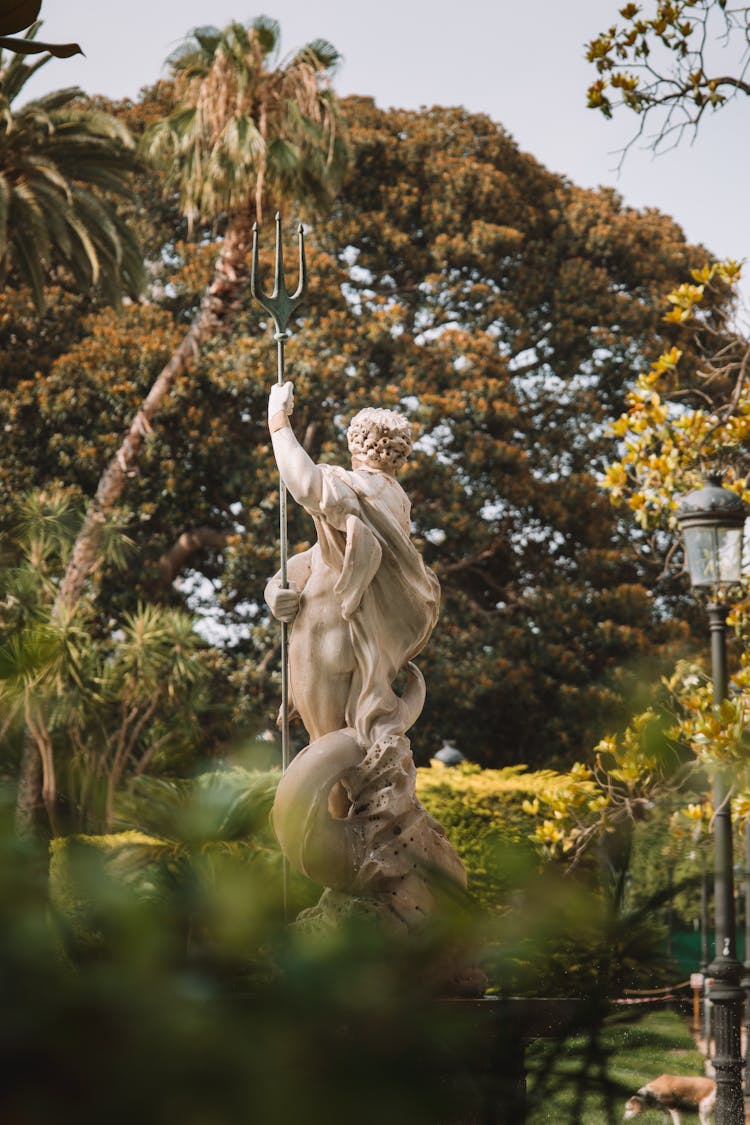 A Neptune Sculpture In A Fountain In A Park 