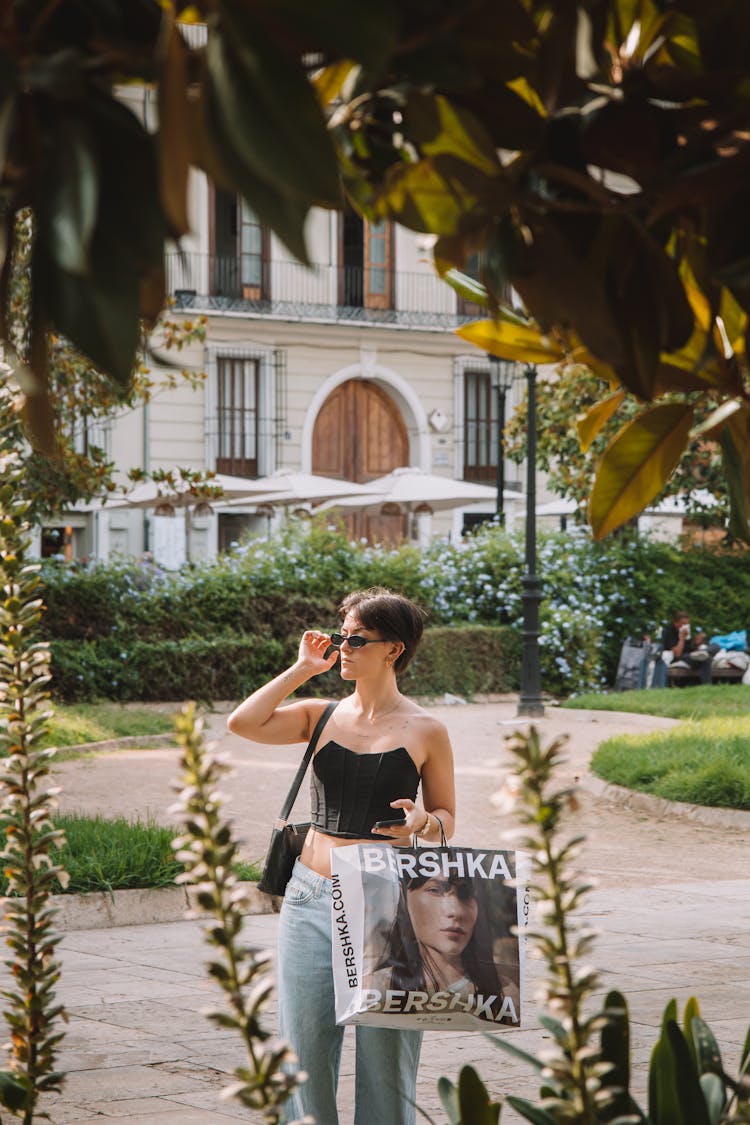 Young Woman With A Shopping Bag Standing In A Park 