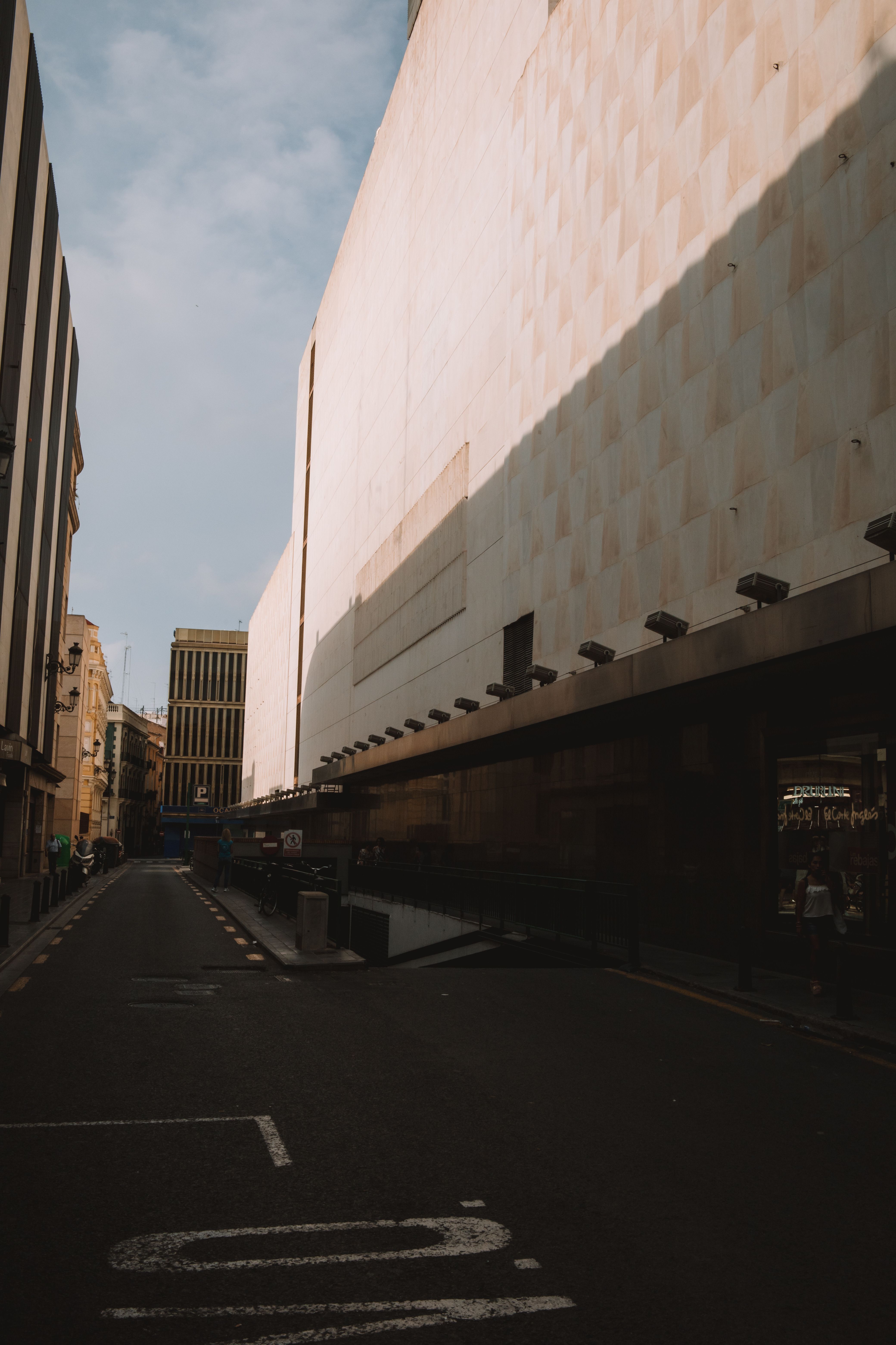 A Narrow Asphalt Street between Modern Buildings in City · Free Stock Photo