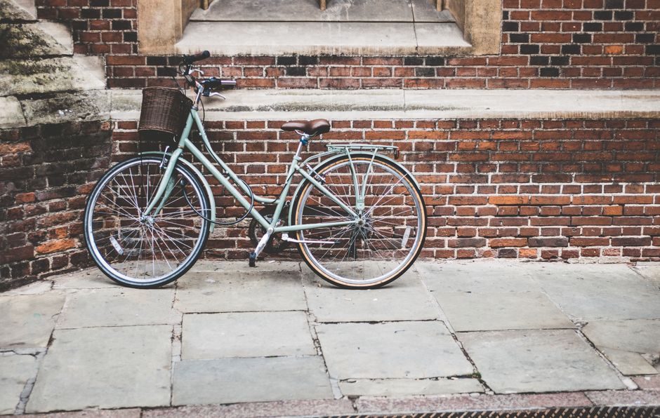 A quaint bicycle with a basket parked against a rustic brick wall, offering a charming and nostalgic scene.