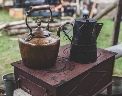 Free Vintage metal kettles on a rustic outdoor wood stove, creating a nostalgic rural scene. Stock Photo