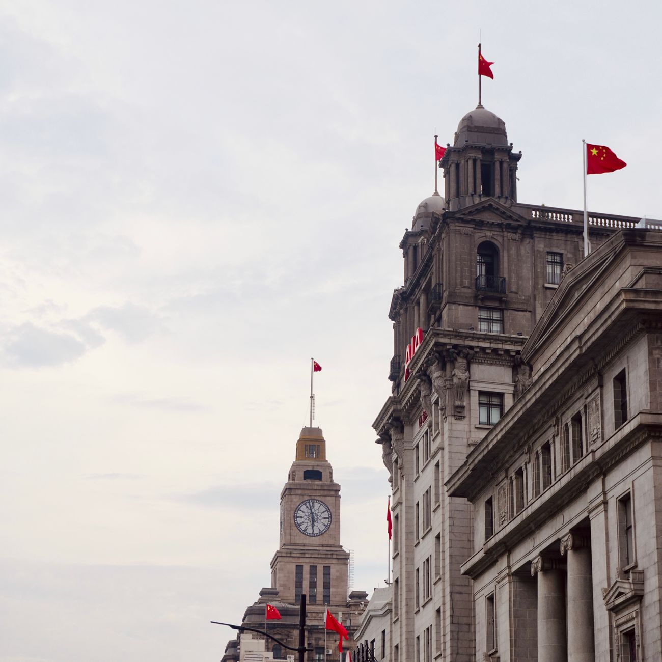 View of Shanghai Custom House with iconic clock tower and flags, showcasing traditional architecture.