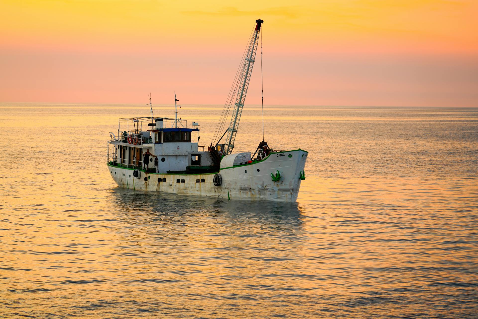 A tranquil evening view of a cargo ship sailing during a vibrant sunset over a calm sea.