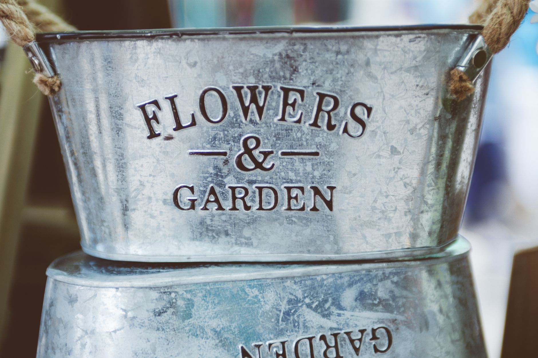 farmhouse patio storage for beginners Close-up view of a galvanized steel bucket with 'Flowers & Garden' text, perfect for rustic decor.