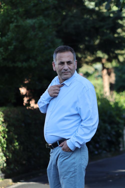 Free Portrait of a middle-aged man standing outdoors in a blue shirt on a sunny day. Stock Photo
