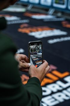 Close-up of hands holding a smartphone, filming a marathon in Chamonix.