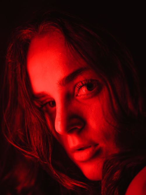 Free Intense close-up portrait of a woman in red lighting, exuding mystery and emotion. Stock Photo