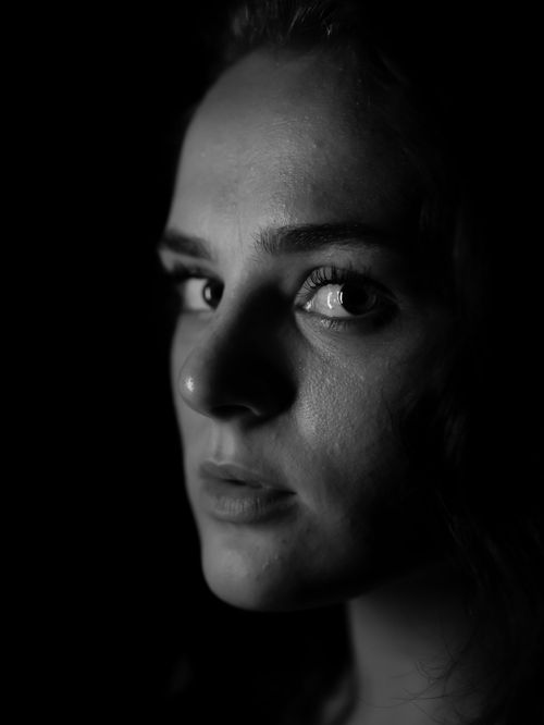 Free Close-up black and white portrait of a young woman with dramatic lighting and shadows. Stock Photo