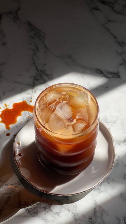 Cold Coffee, Matcha Lattes, and Iced Drinks: How to Make Café-Quality Beverages at Home 2 Large glass jar of cold brew coffee steeping on a kitchen counter with coarsely ground coffee visible through the glass