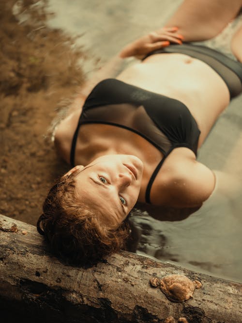 Woman in Swimsuit Lying in Water at Beach