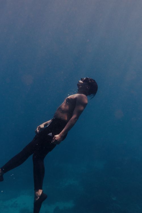 Free A serene image of a scuba diver floating peacefully underwater in deep blue waters. Stock Photo