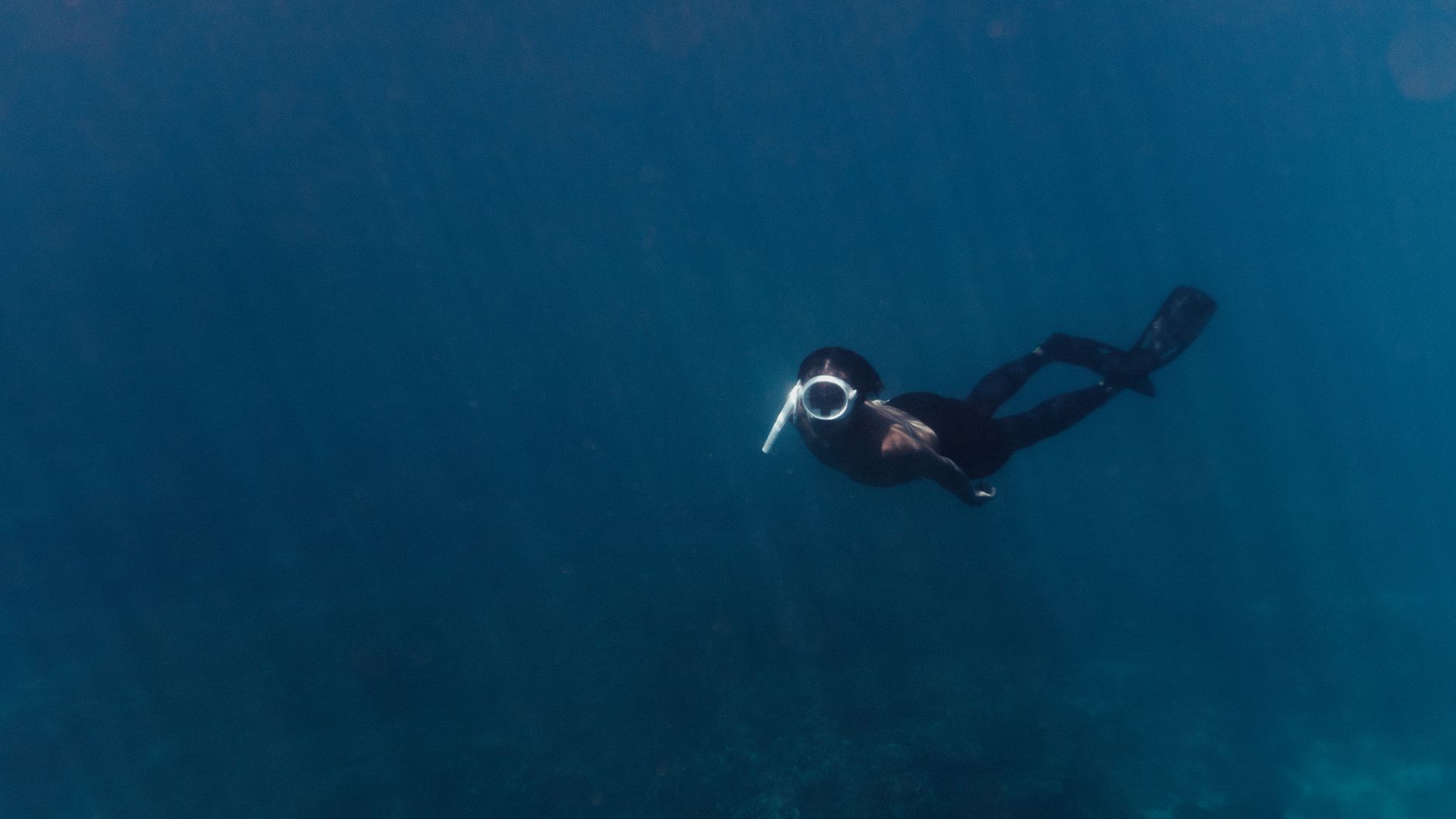 Un buceador explorando el profundo océano azul, capturando la esencia de la aventura y exploración submarina.