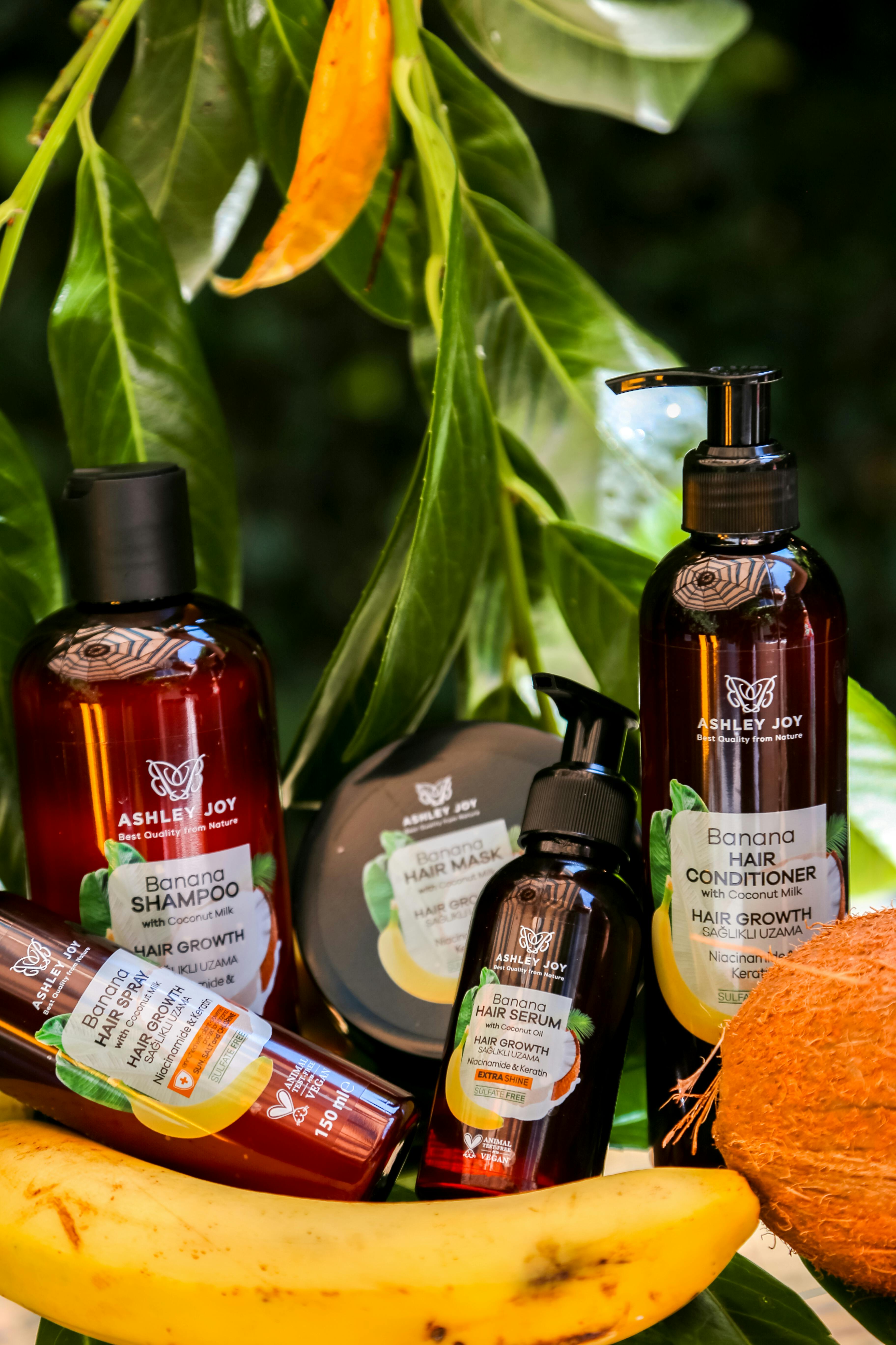 Collection of banana-infused hair care products surrounded by tropical fruits and leaves.