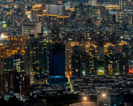 High angle night view of a brightly lit urban cityscape with skyscrapers.