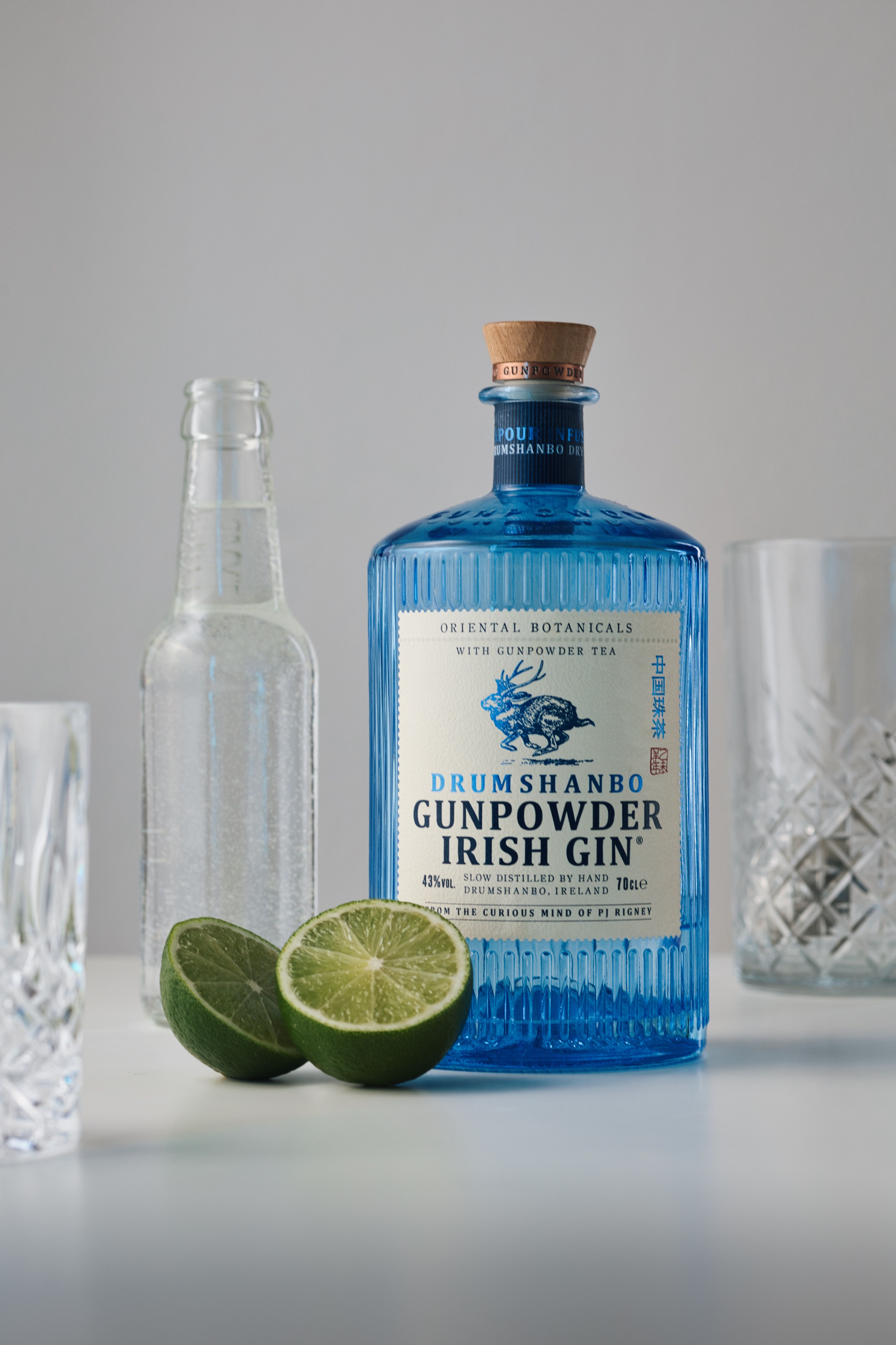 Still life of Drumshanbo Gunpowder Irish Gin with lime and glasses, perfect for cocktail inspiration.