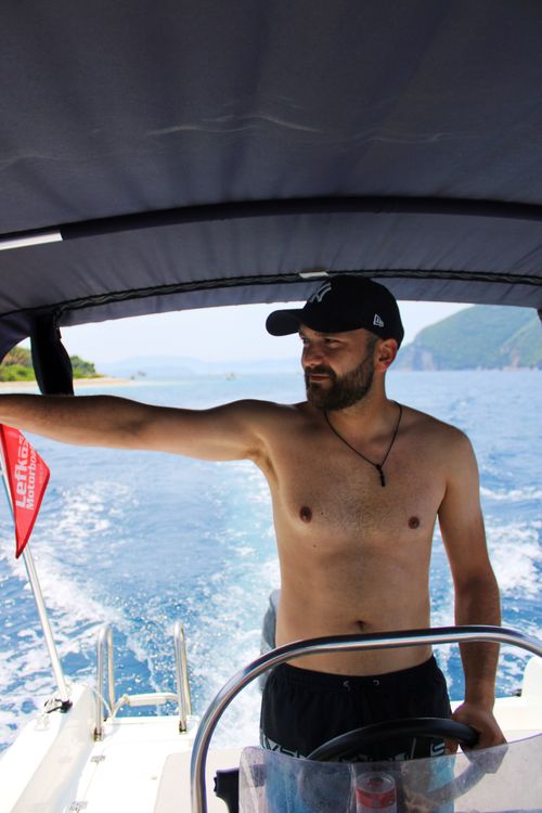 Free A topless man steering a motorboat in the scenic waters of Lefkada, Greece. Stock Photo