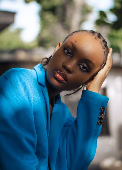 Free A striking portrait of a woman in a vibrant blue blazer, set against a blurred outdoor backdrop. Stock Photo