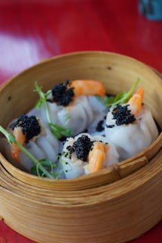 Delicious shrimp dumplings topped with black caviar served in a bamboo steamer, perfect for food photography enthusiasts.
