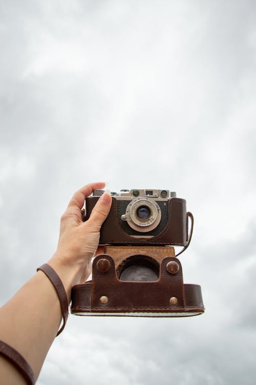 Hand Holding Camera up to Cloudy Sky