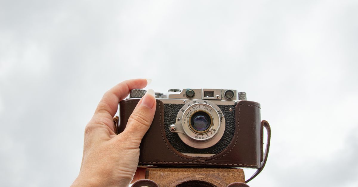 Hand With Camera Hand Holding Camera up to Cloudy Sky · Free Stock Photo