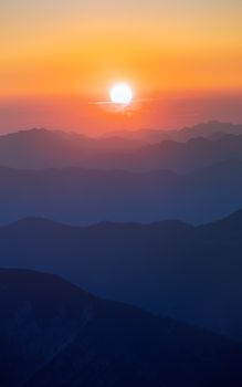 Captivating sunset scene with vibrant hues over serene mountain layers.