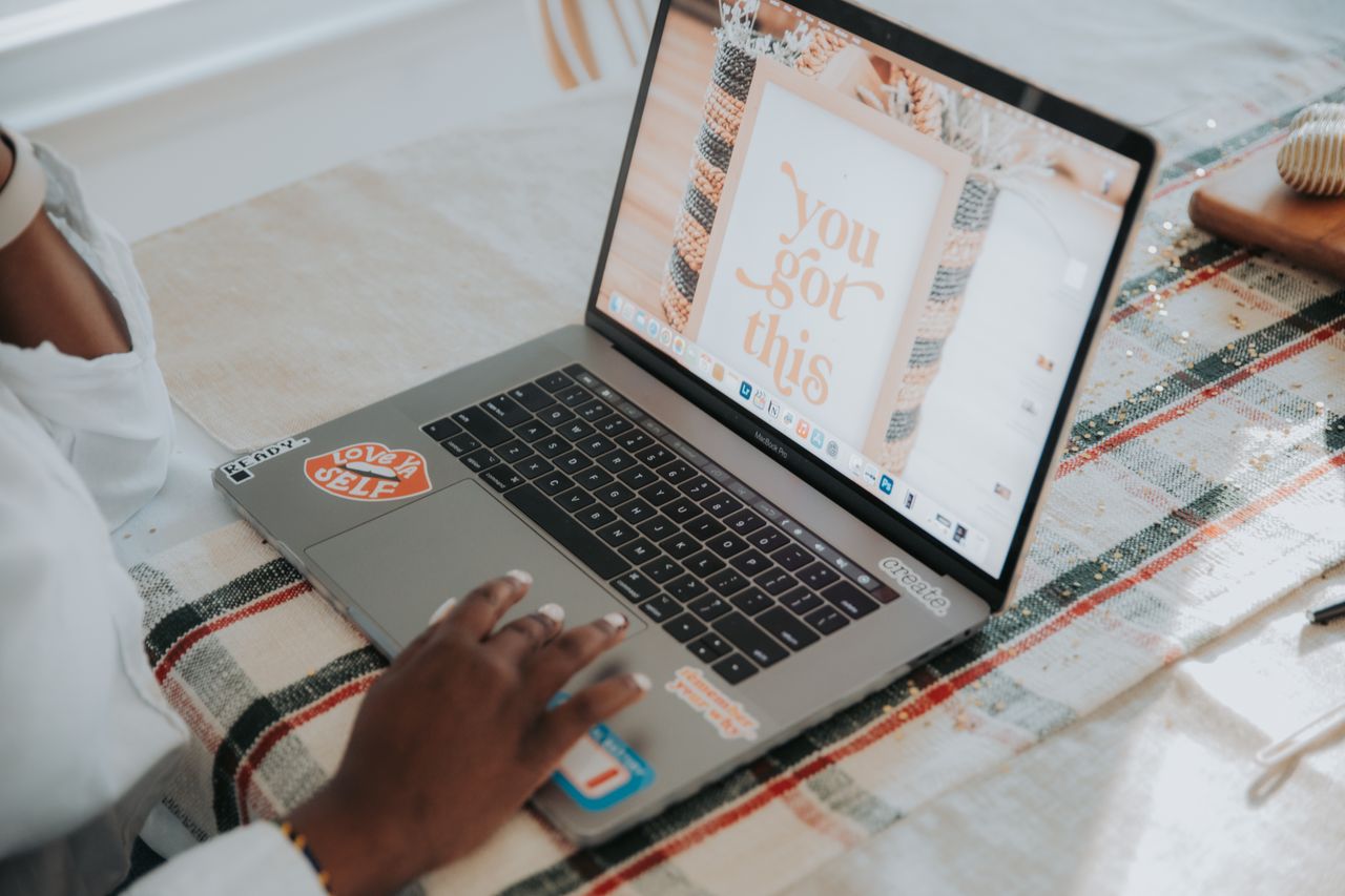 close up of hands on a laptop with a motivational wallpaper indoors on