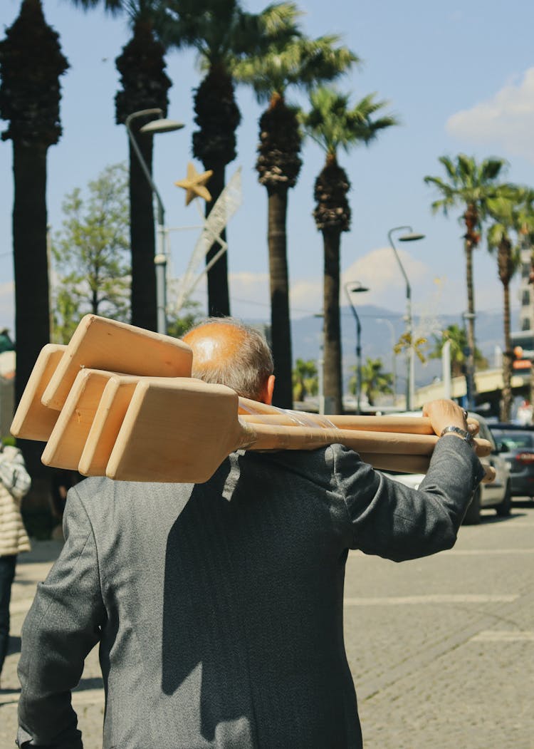 Man Carrying Wooden Paddles On Shoulder