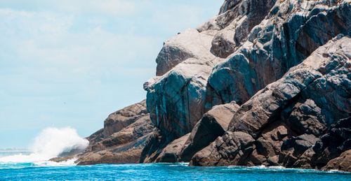 Free Vivid blue ocean waves crashing against towering rocky cliffs under a bright sky. Stock Photo