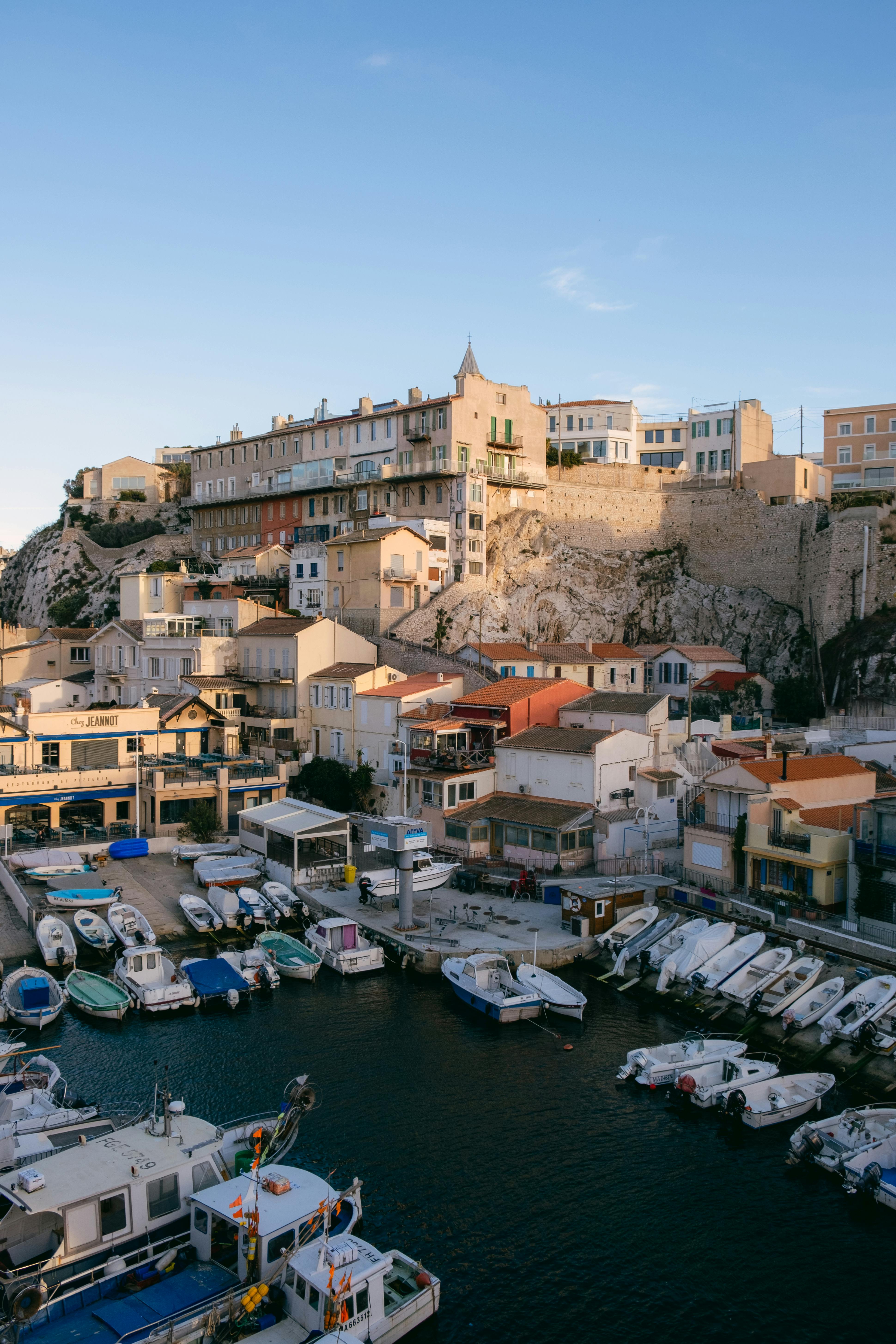 Charming harbor scene with boats and picturesque clifftop buildings at mid-day.
