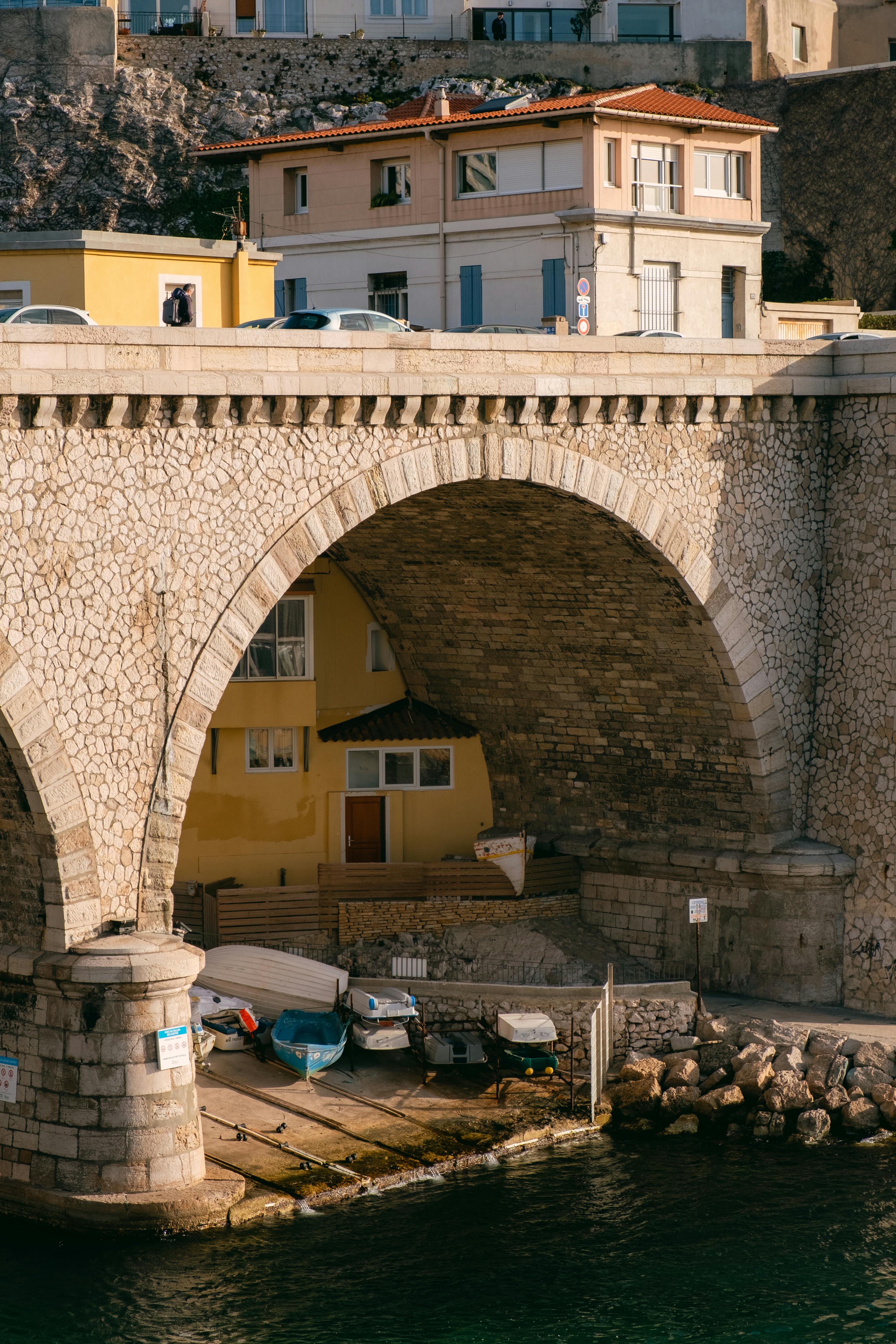 Stone arch bridge over a calm waterfront in a picturesque urban setting.