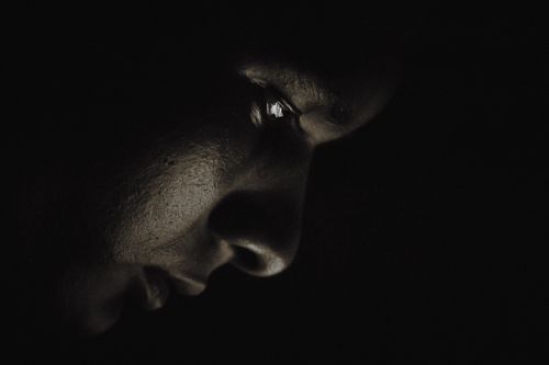 Free Moody close-up portrait of a person illuminated by soft light, creating dramatic shadows. Stock Photo