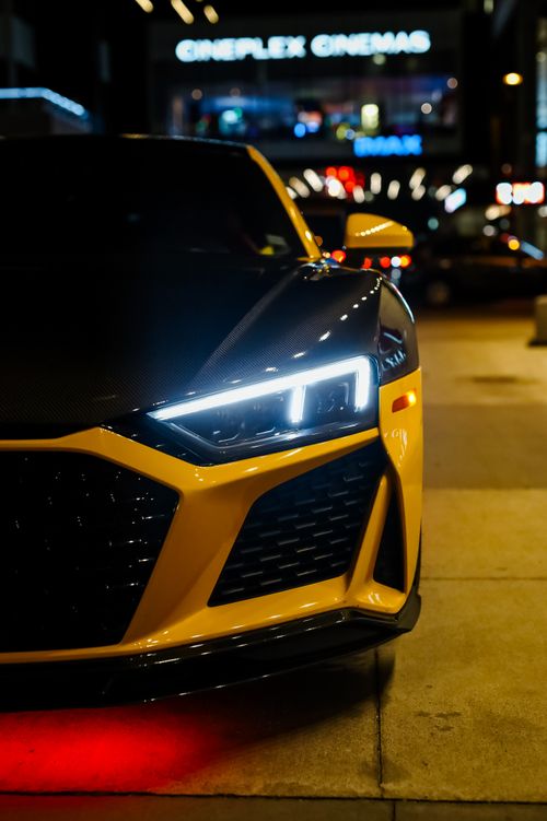 Free Yellow sports car with bright headlights parked on an urban street at night. Stock Photo