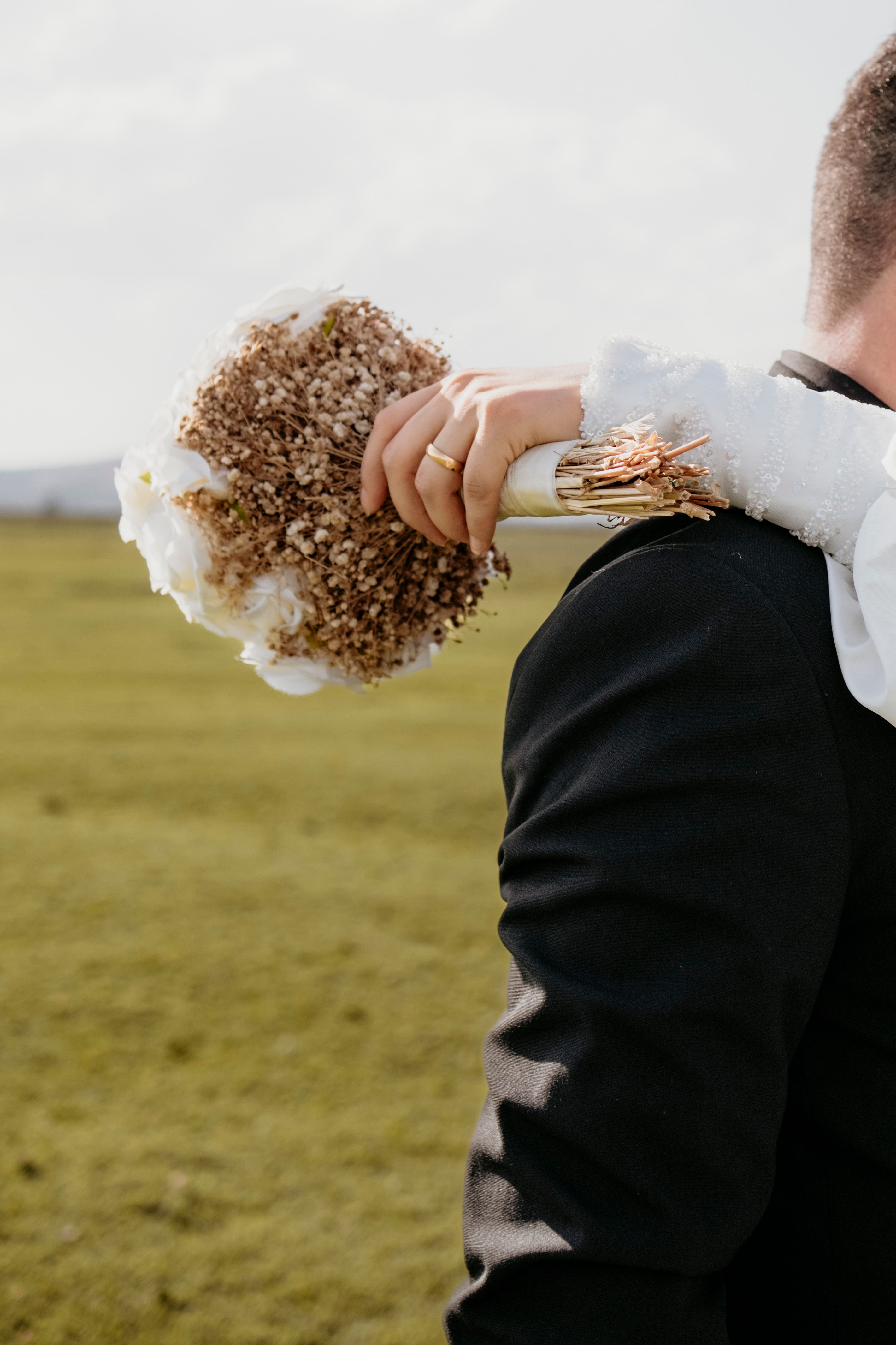 The couple outdoors, bouquet in hand