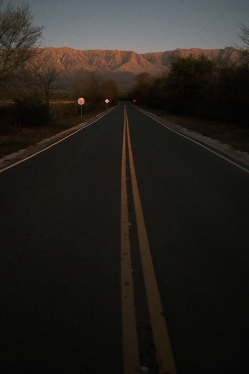 Fotos de stock gratuitas de amanecer, camino rural, doble linea amarilla