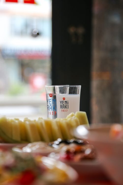 Free Two Yeni Raki glasses on a table with fresh melon slices, creating a cozy indoor setting. Stock Photo