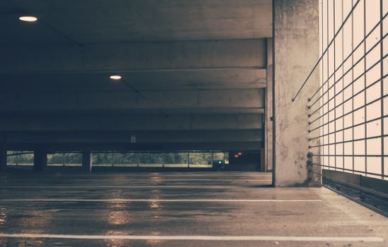 Deserted indoor parking garage with industrial design and wet concrete floor creating a moody ambiance.