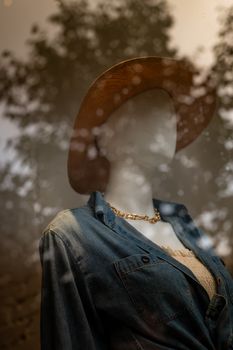 Fashionable mannequin in a window display featuring a casual outfit with a hat.